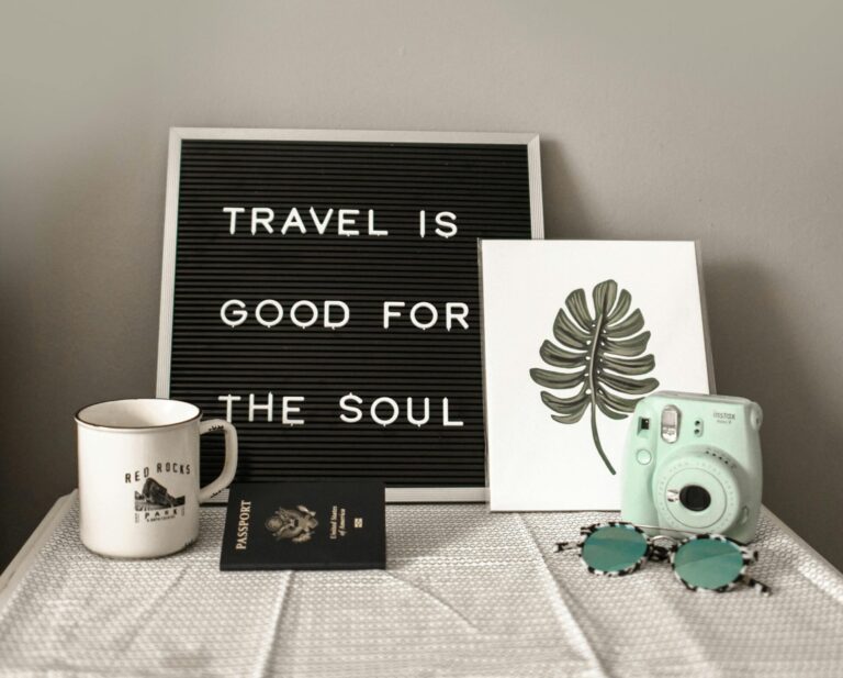 A travel-themed flat lay with a camera, coffee, and motivational quote.